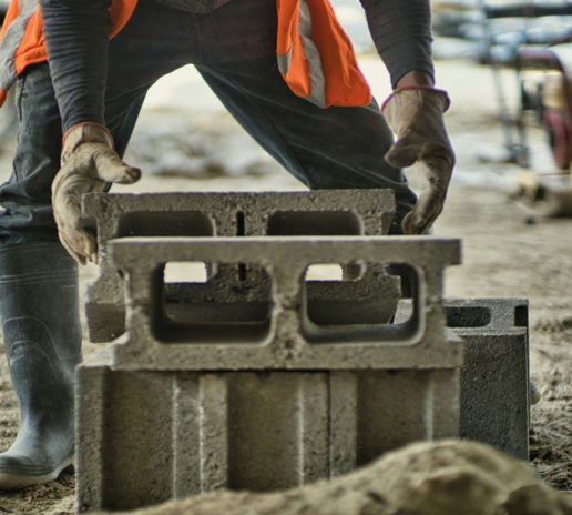 a man in an orange vest is working on a concrete block